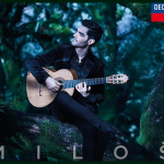 man playing the guitar with a forest in the background
