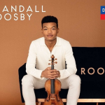 Randall Goosby Roots cd cover. A man sits on a couch holding his violin.
