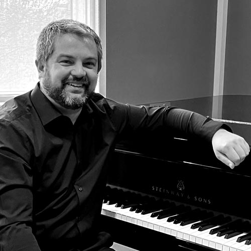 man leaning against a piano - Steven Joinson