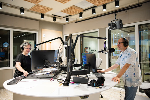 Two radio hosts standing in front of microphones