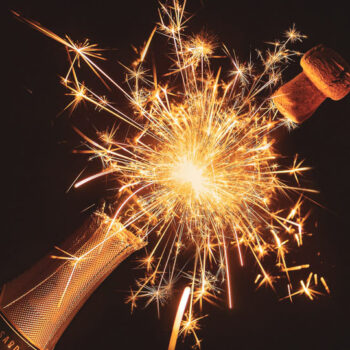 Cork popping off champagne bottle with sparks