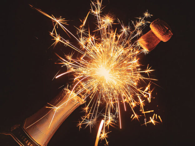 Cork popping off champagne bottle with sparks