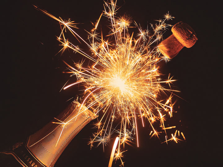 Cork popping off champagne bottle with sparks