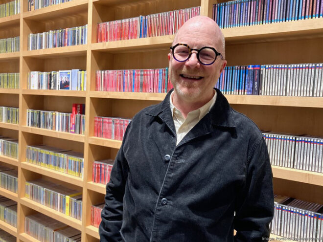 Fred Child, president and CEO of All Classical Radio, stands in front of a wall of CDs at the station's headquarters in KOIN Tower. Photo courtesy of Portland Business Journal.